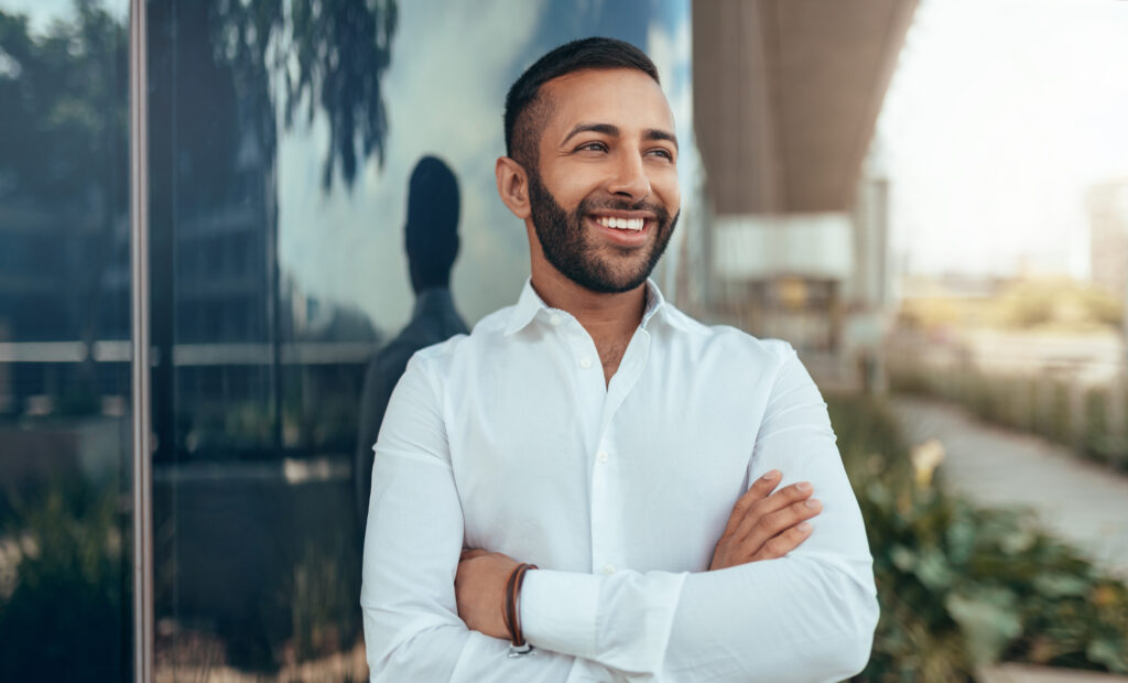 young confident smiling indian man with his arms crossed