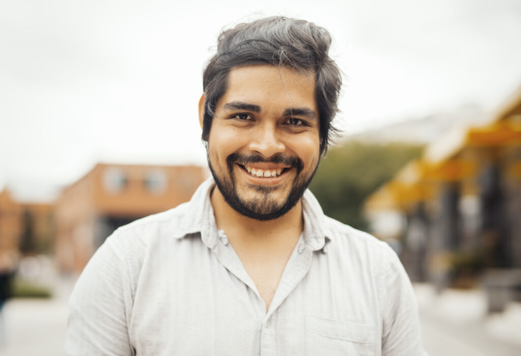 brunette latin man smiling outside