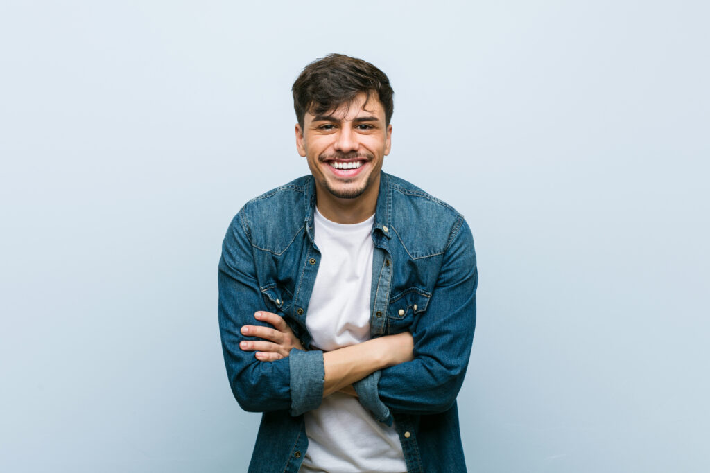 Smiling man with arms crossed on light blue background
