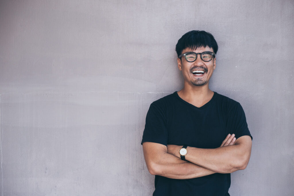 Smiling man arms crossed on grey background