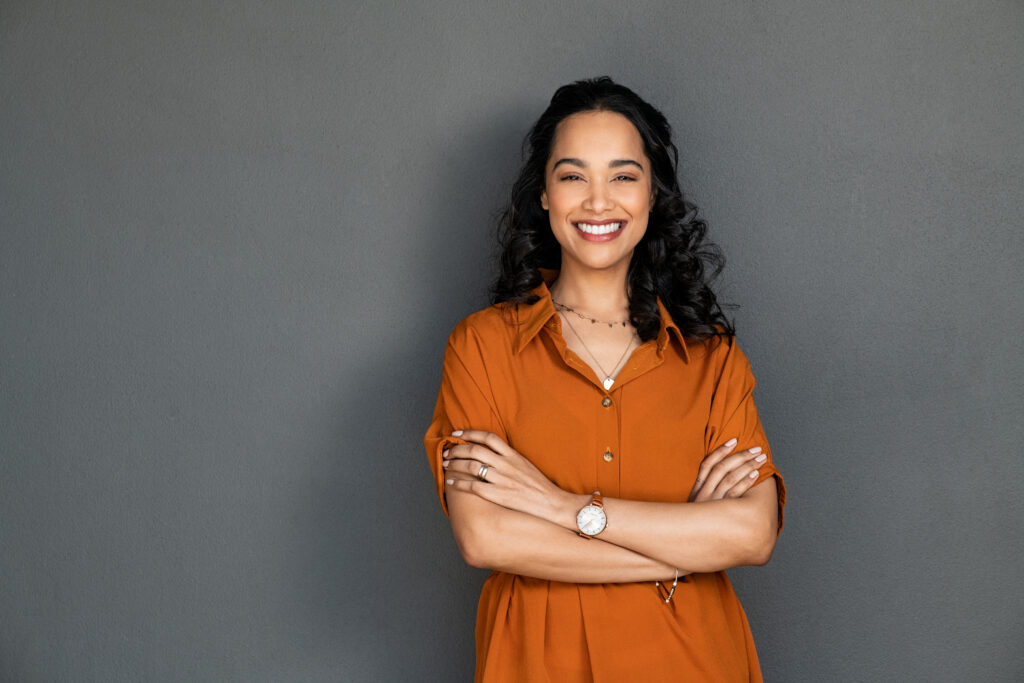 Smiling woman in orange shirt crossing arms