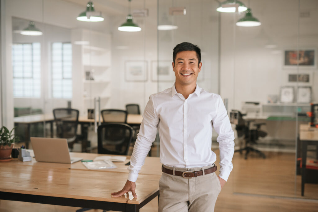 smiling businessman standing next to table