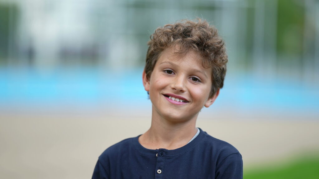 Happy young boy standing outside